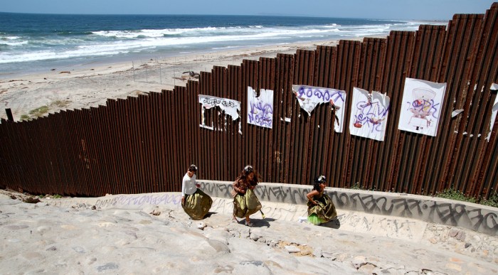 Tres niñas en vestido de quinceañeras juegan en Tijuana al lado del muro de la frontera México-USA. Fotografía: Romel Jacinto. Flickr. CC.
